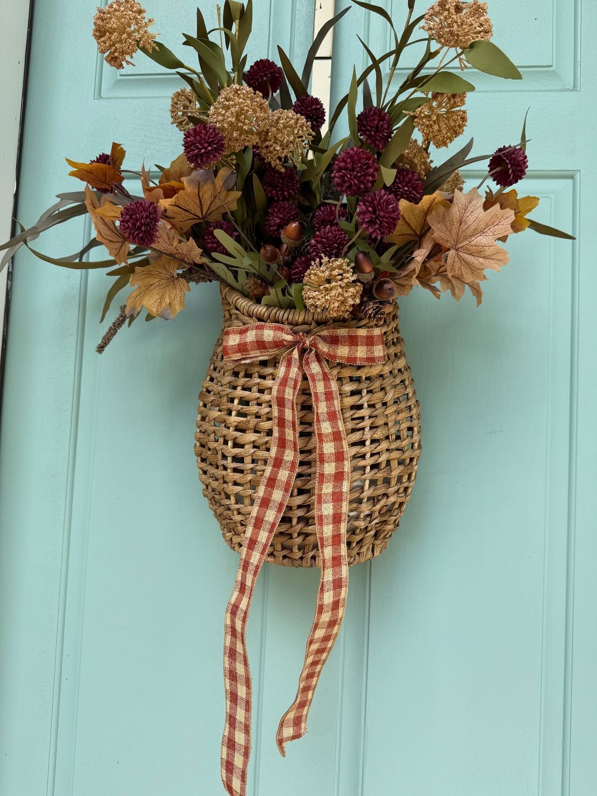 Flower filled hanging basket on a front door as a vintage fall wreath alternative