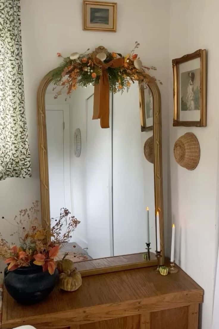 Dried floral swag with velvet ribbon draped across an arched gold mirror