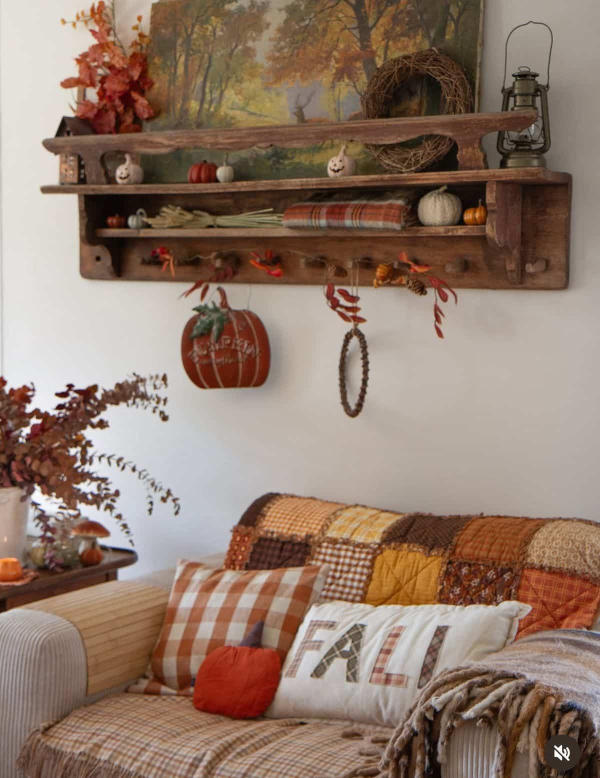 Layered vintage autumn shelf above a sofa with a patchwork quilt and gingham cushions