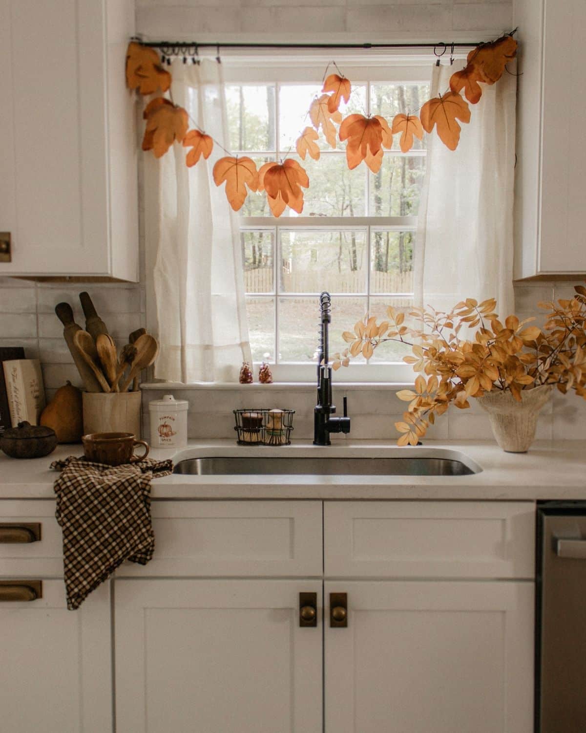Autumn leaf garland strung across a farmhouse kitchen window