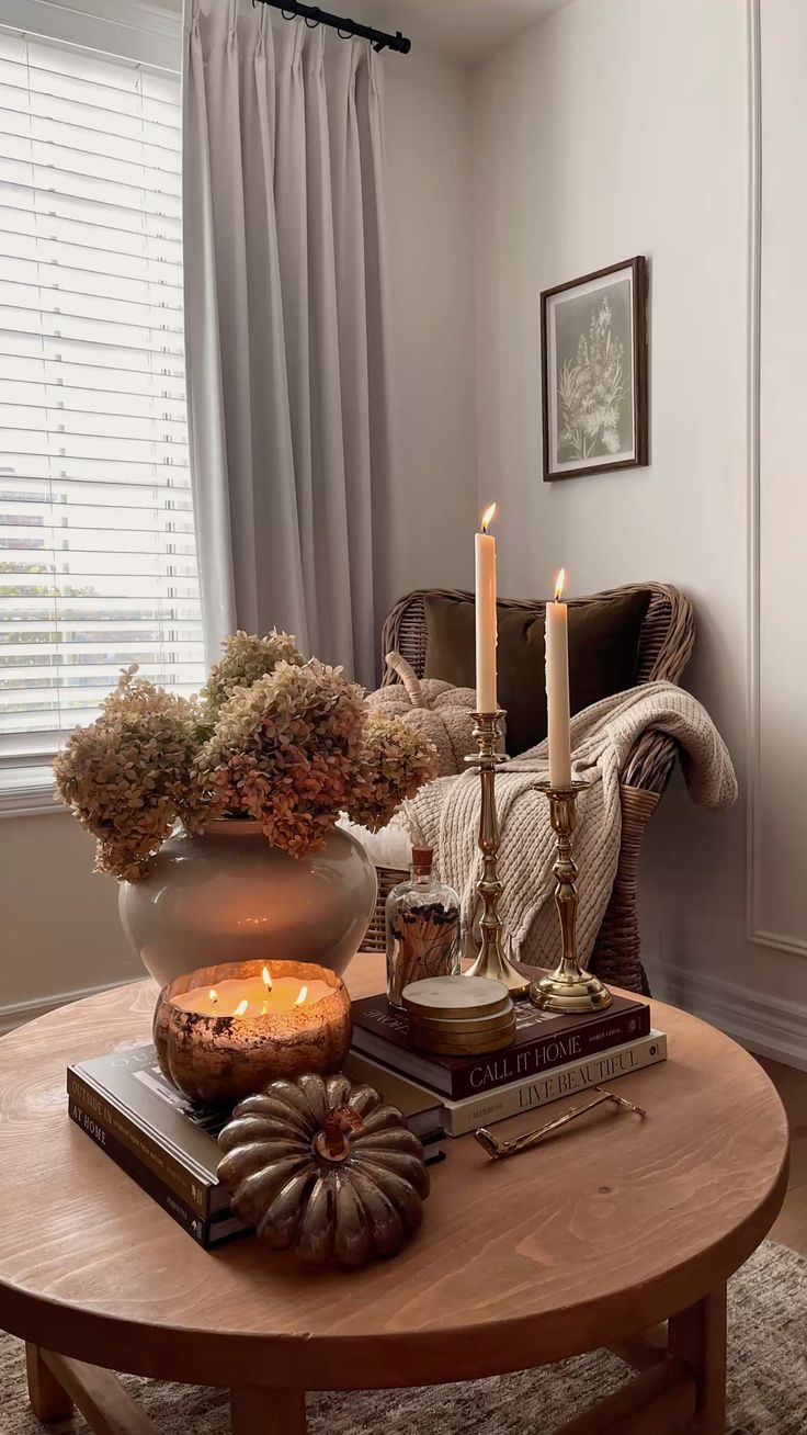 Cozy fall coffee table vignette with candles, books, dried hydrangeas and a mercury glass pumpkin