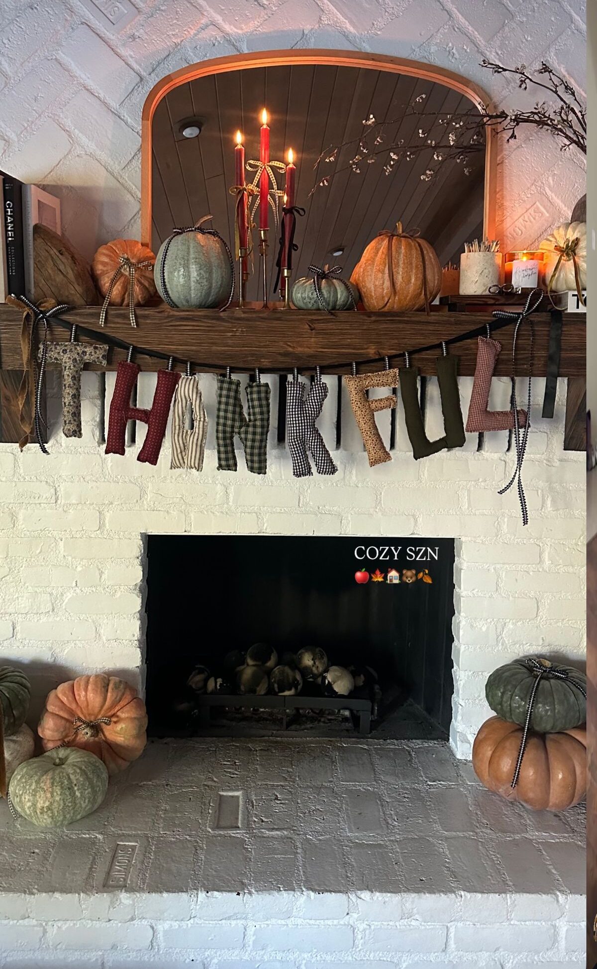 Handmade fabric Thankful banner strung across a white brick fireplace mantel with heirloom pumpkins