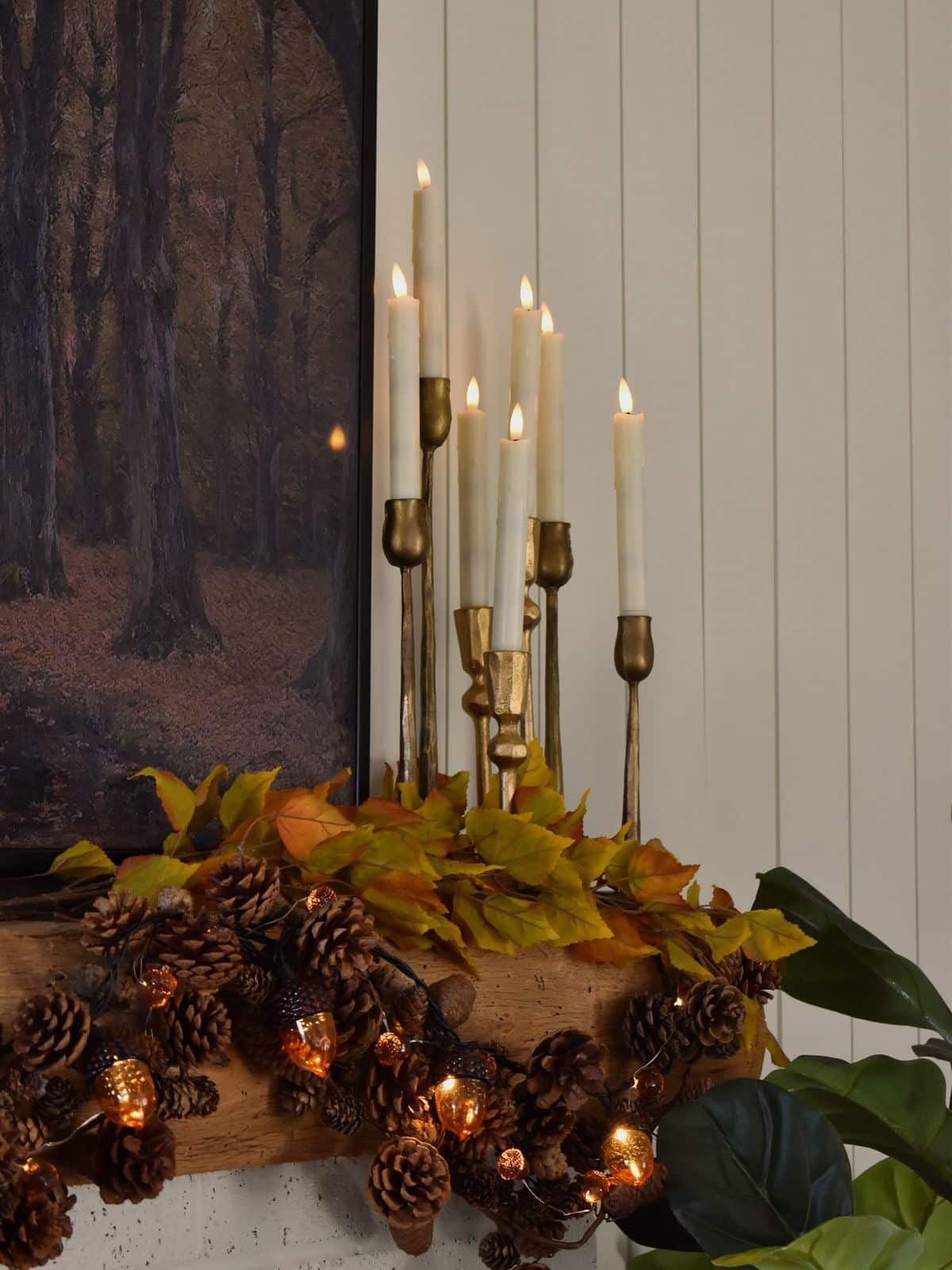 Mismatched brass candlesticks styled with an autumn leaf and acorn garland