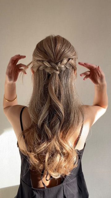 Light brown wavy hair with braided sections knotted together into a half up crown.