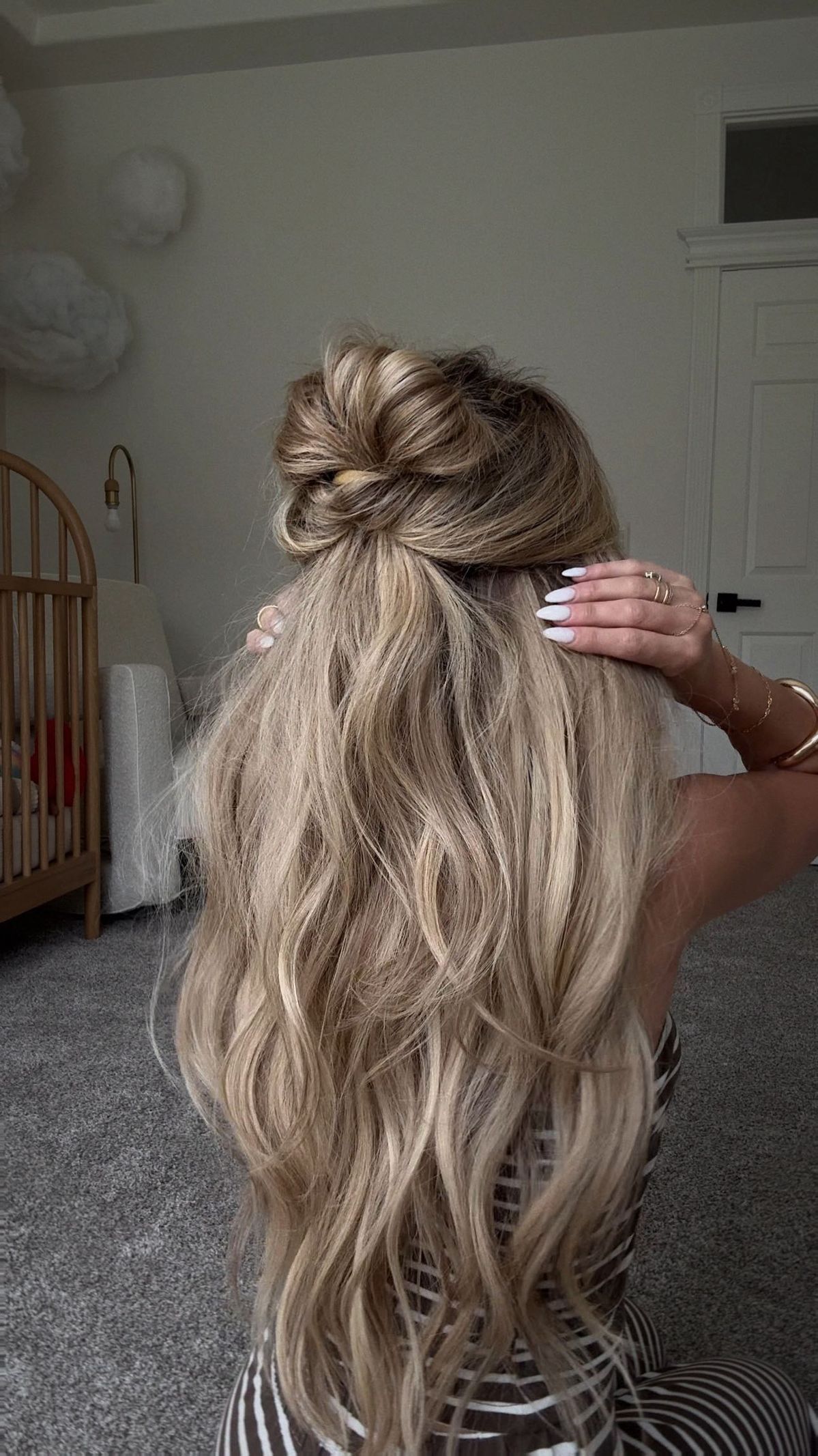 Long blonde hair in a full voluminous half up bun with waves left down.