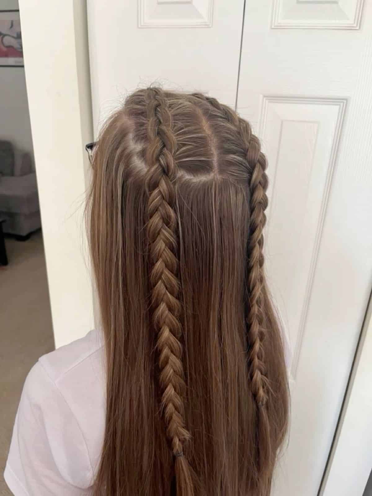 Long straight brown hair with three small braids running into a half up style.