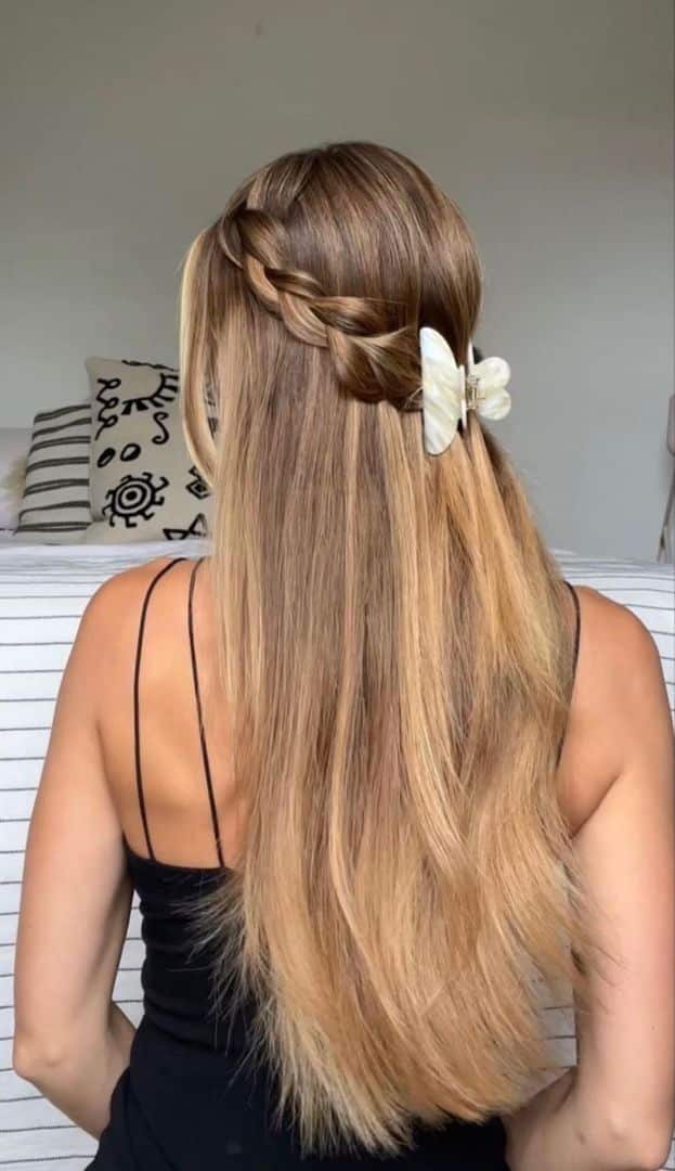 Long blonde hair with a dutch braid across the crown fastened with a white claw clip.