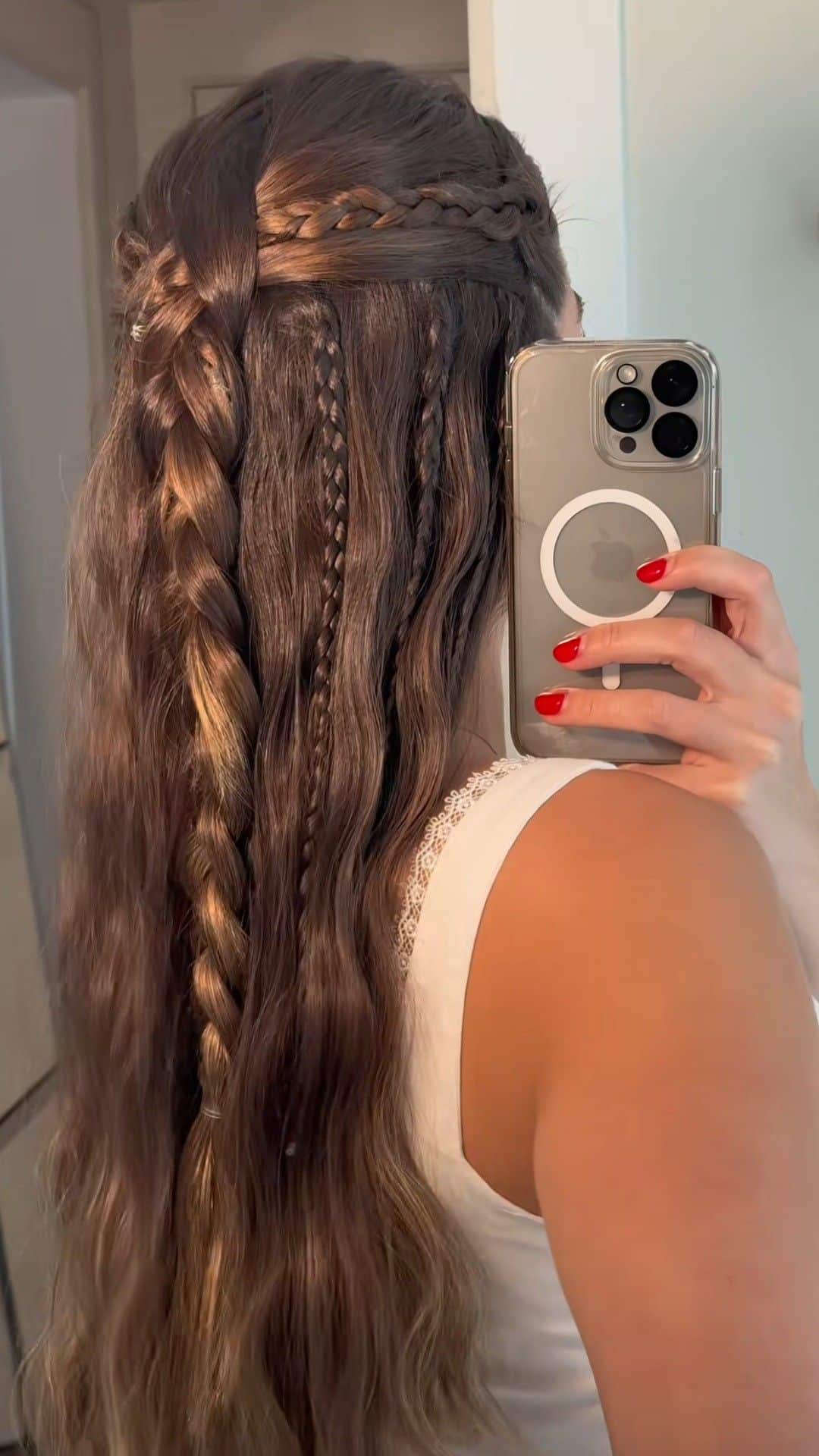 Long brunette waves styled half up with layered braids of varying thickness.