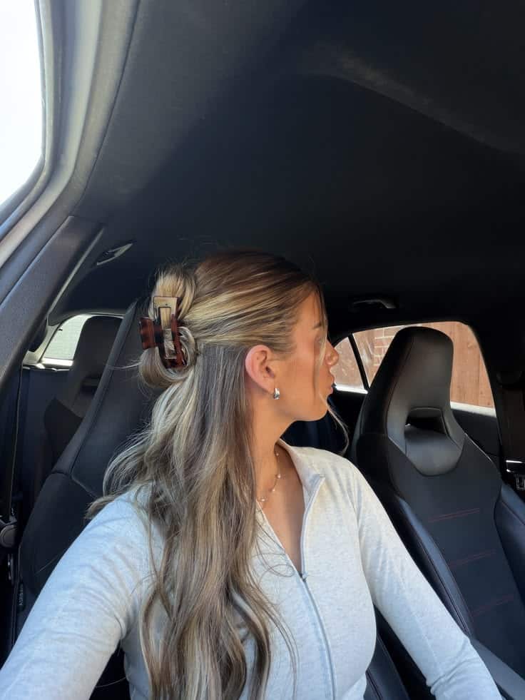 Long blonde hair in a twisted half up bun secured with a tortoiseshell claw clip.