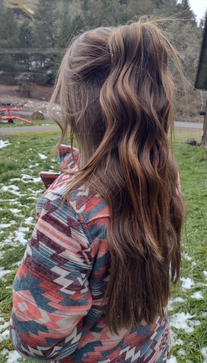 Long wavy brunette hair in a deliberately messy half up ponytail.