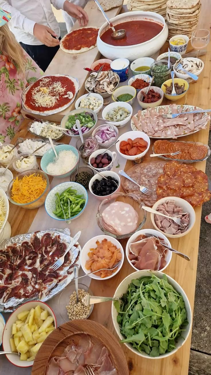 Gourmet pizza topping bar spread with cured meats, cheeses, and fresh greens