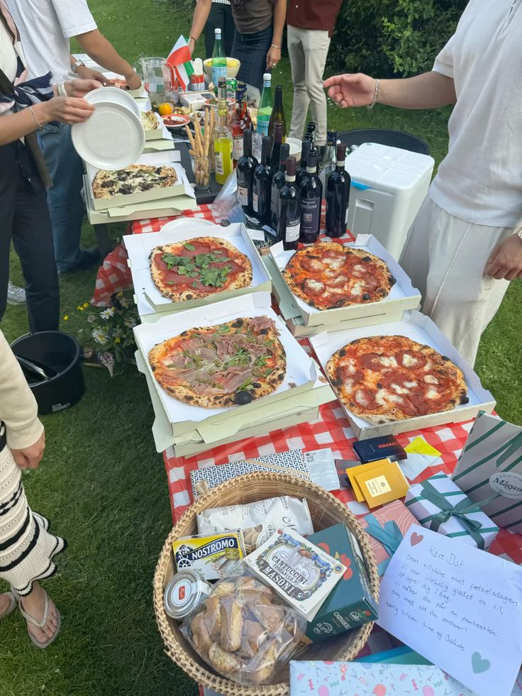 Artisan pizza boxes open on a gingham picnic table outdoors