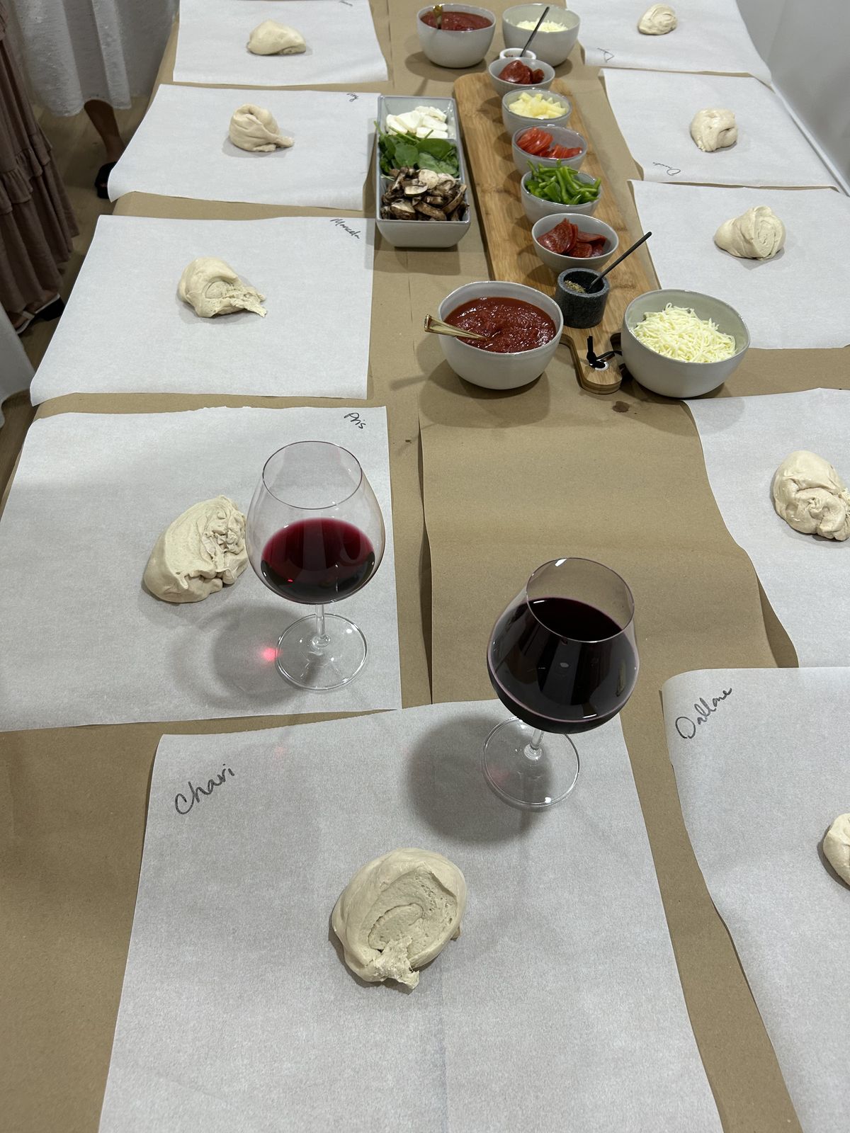 Wine glasses and individual dough balls laid out for a pizza making dinner party