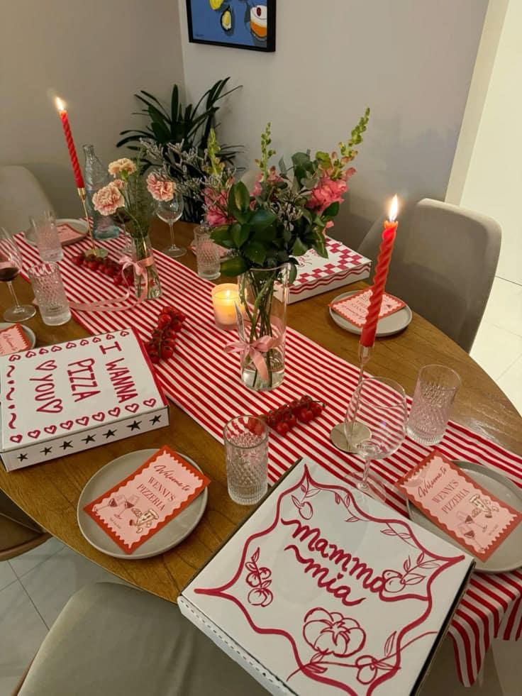 Hand lettered pizza boxes used as place settings on a red and white striped table