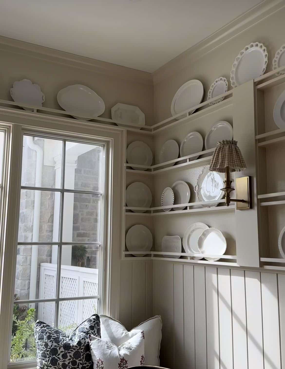 White plate rails running around the top of a room filled with white plates and platters