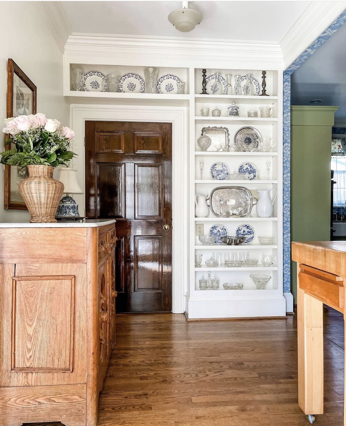White built-in display shelves framing a doorway filled with blue and white china and glassware