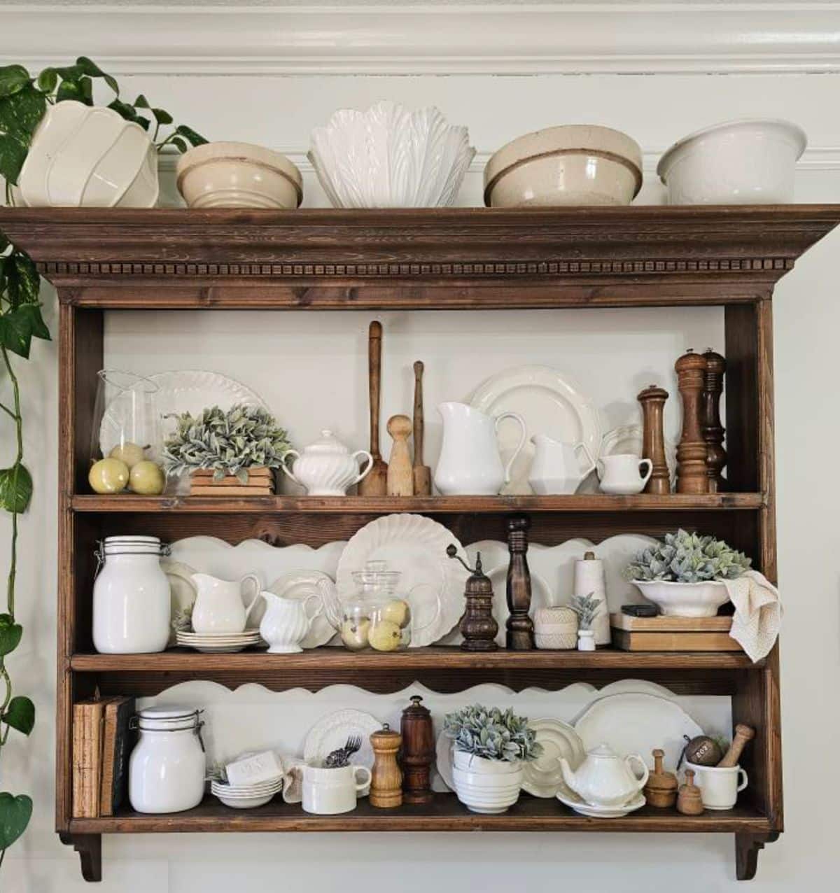 Wooden wall shelf displaying a creamy white ironstone collection of plates, pitchers, and bowls