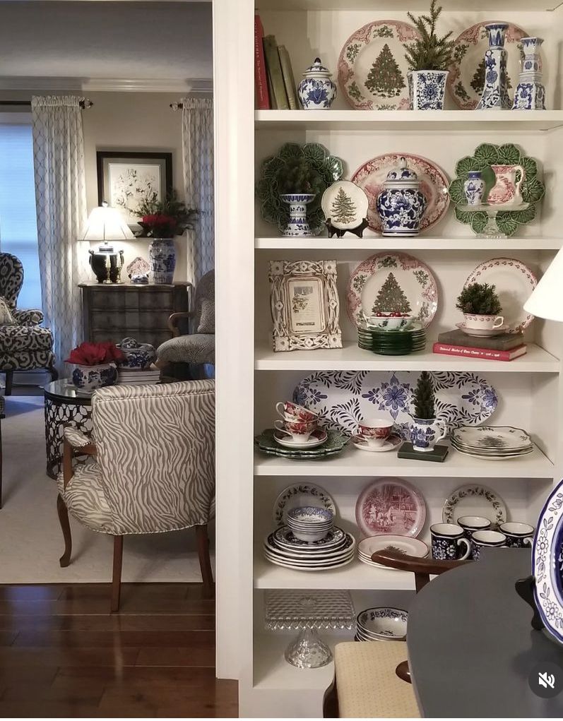 White built-in shelves displaying red and green Christmas transferware plates