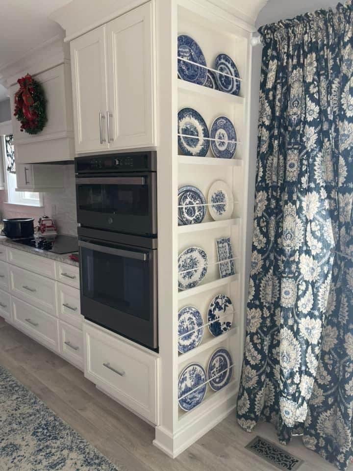 Plate rack built into the end of white kitchen cabinets filled with blue and white plates