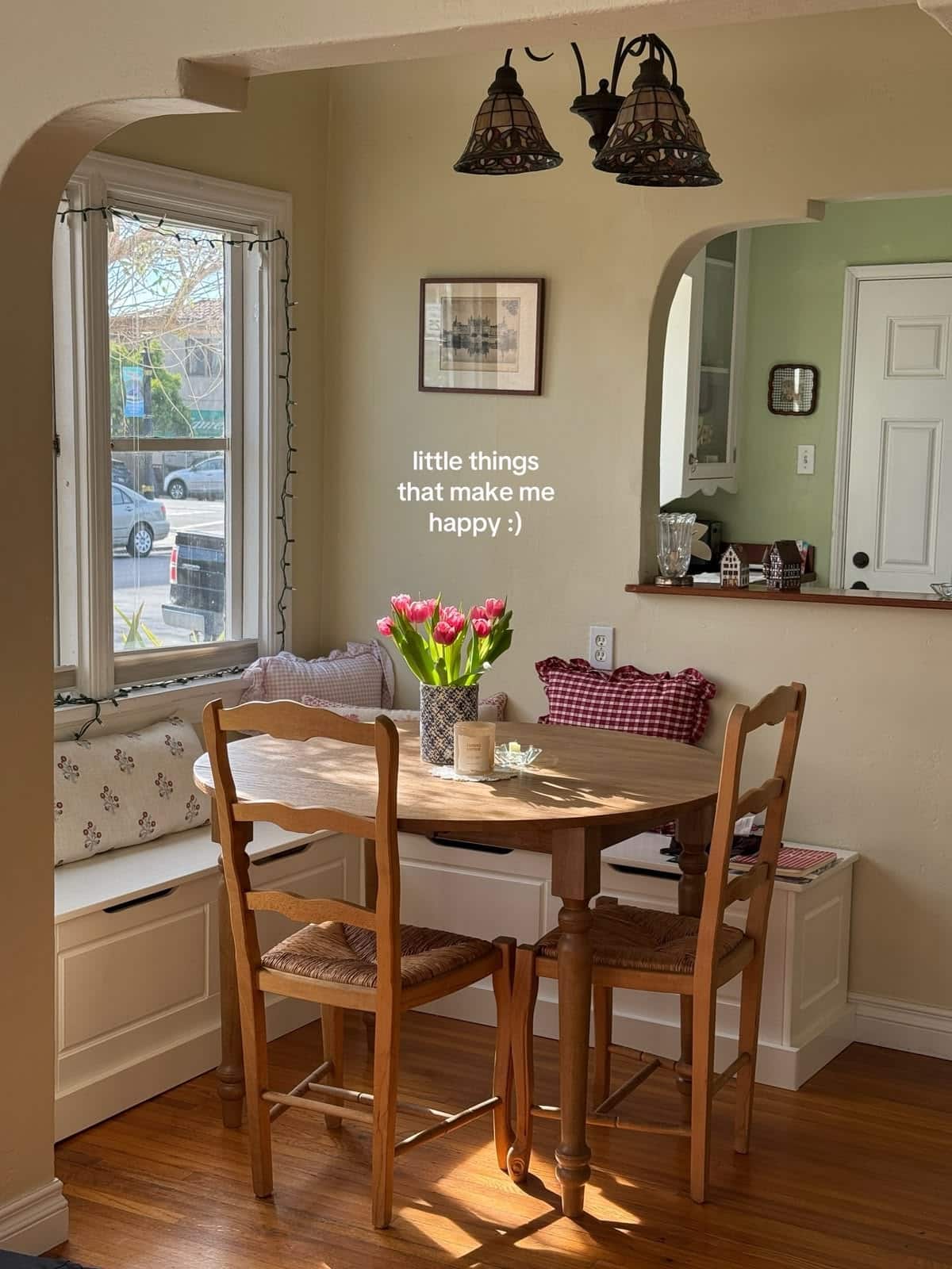 Corner bench layered with mixed gingham and floral cushions beside rush-seat ladderback chairs