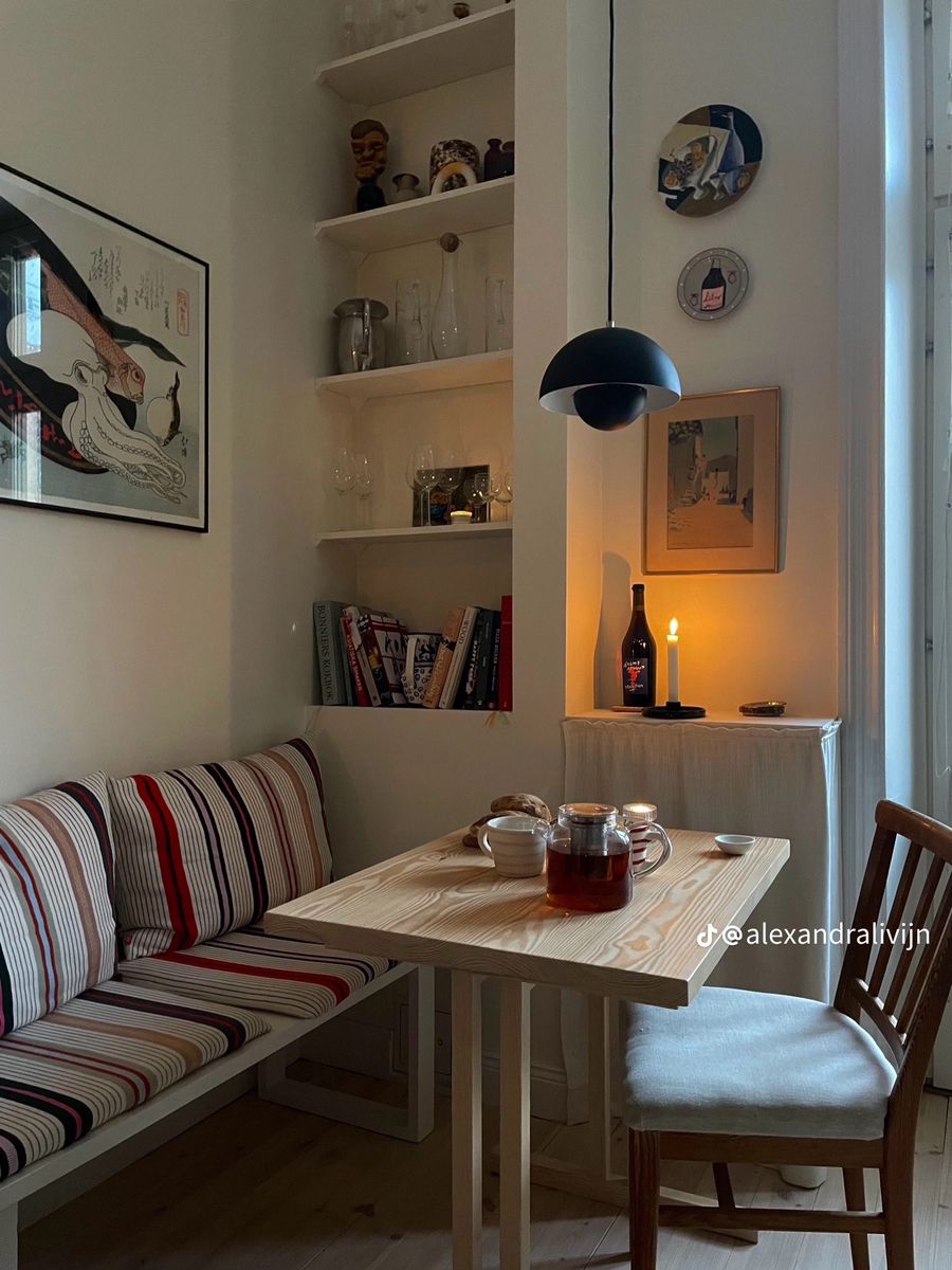 White bench with a bold striped cushion beside built-in alcove shelving in a candlelit corner