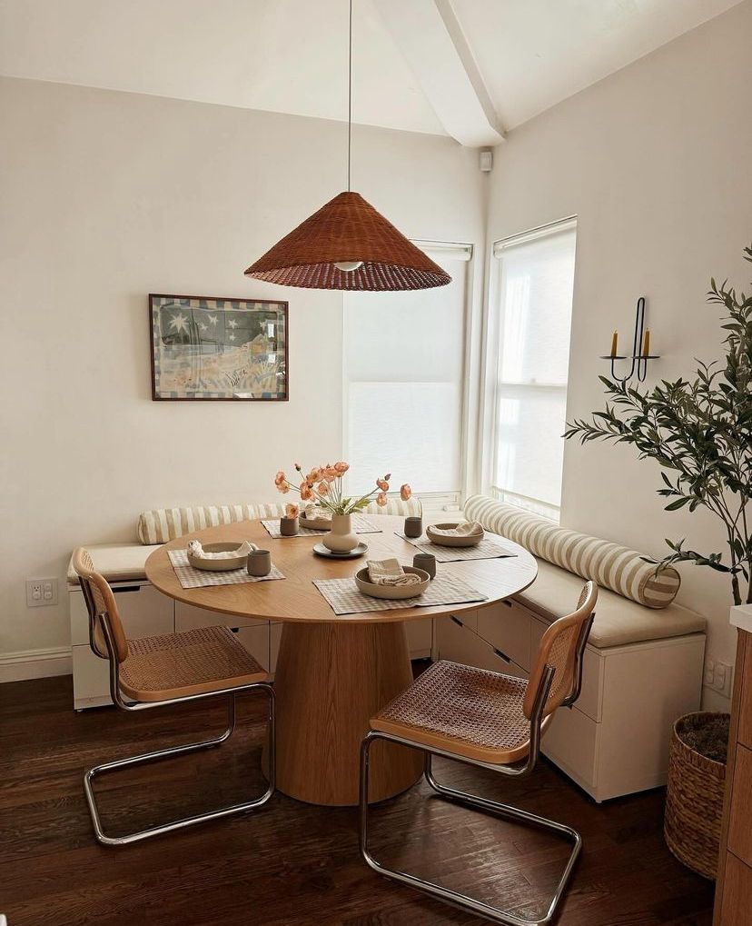 Wraparound cream banquette with striped bolster cushions around a round oak pedestal table