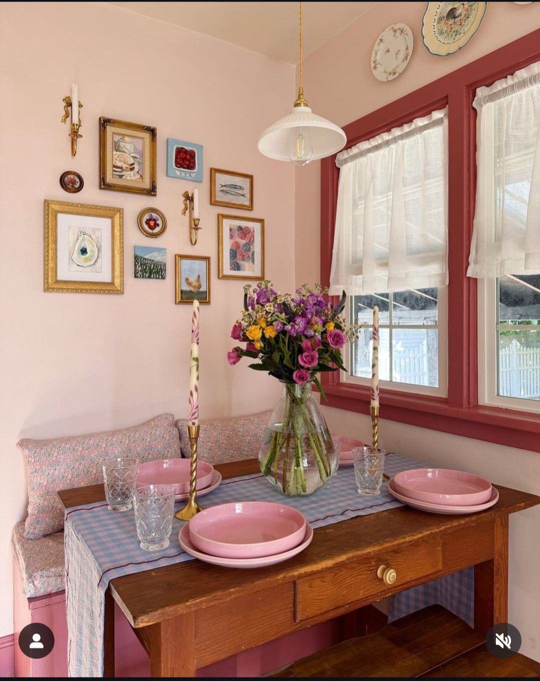 Blush pink corner with a floral banquette, vintage farm table and a layered gallery wall of framed art