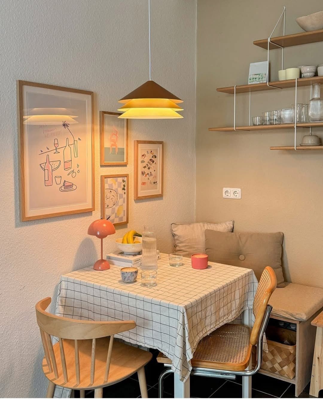 Corner cushioned bench mixed with a spindle chair and a cane chair at a table with a checked tablecloth below a playful gallery wall