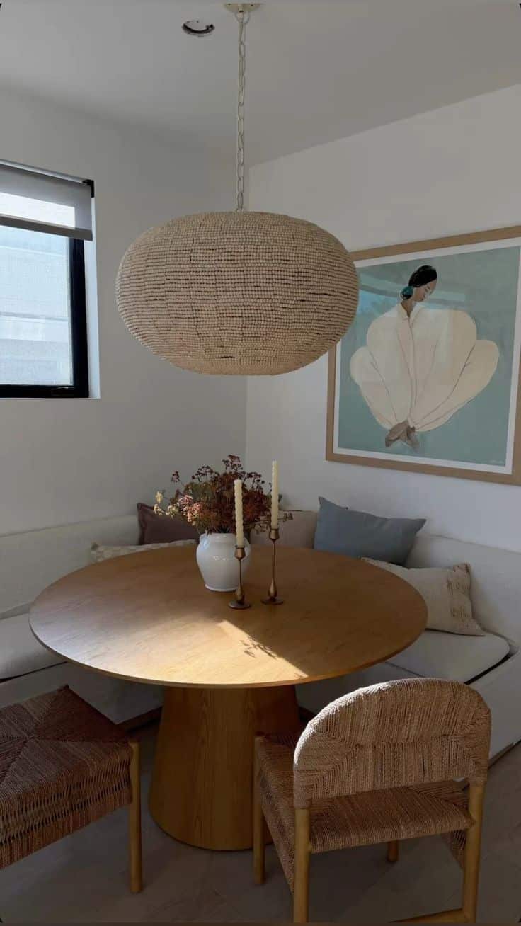 Deep upholstered sofa-style corner banquette with a round timber table and a large woven rattan pendant light