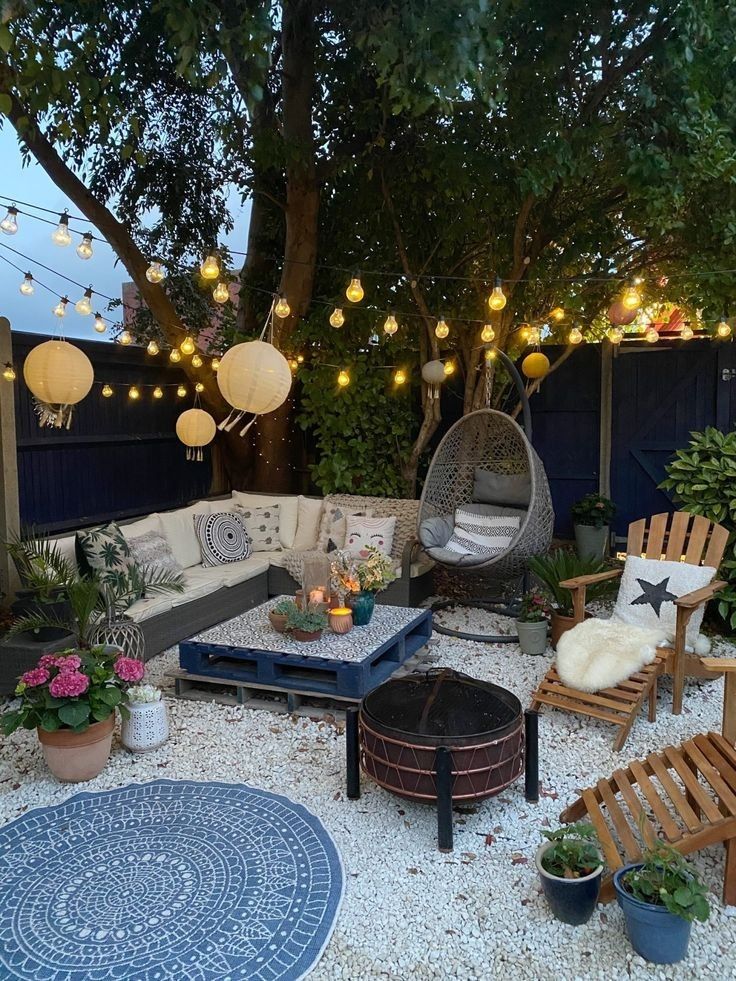 Boho garden corner with a grey corner sofa, hanging paper lanterns, festoon lights and a rattan egg chair