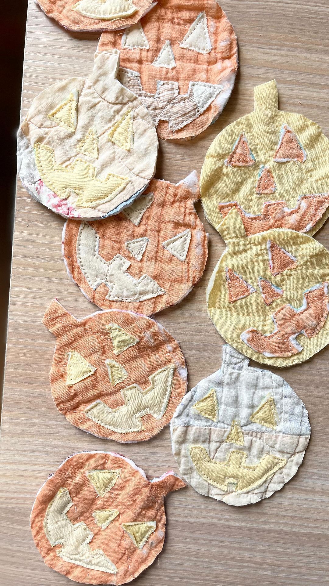 Quilted pumpkin face appliqués in faded orange, yellow and cream fabric scraps
