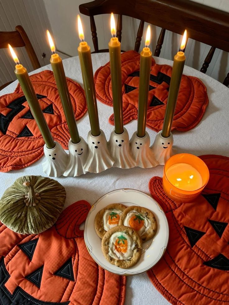 Ceramic ghost candle holders with green tapers on jack-o'-lantern placemats