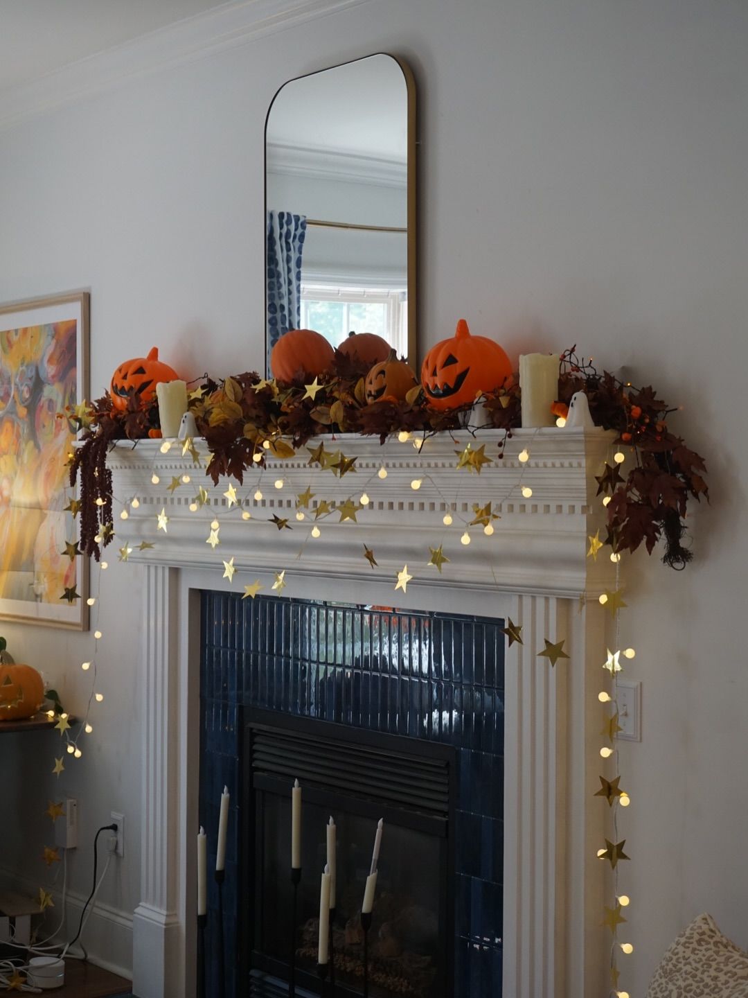 Mantel dressed with jack-o'-lanterns, autumn leaves and gold star string lights