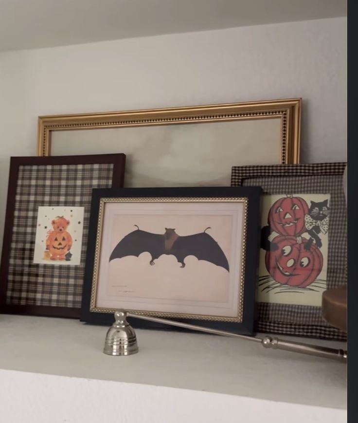 Framed vintage Halloween prints matted on plaid and gingham fabric on a shelf