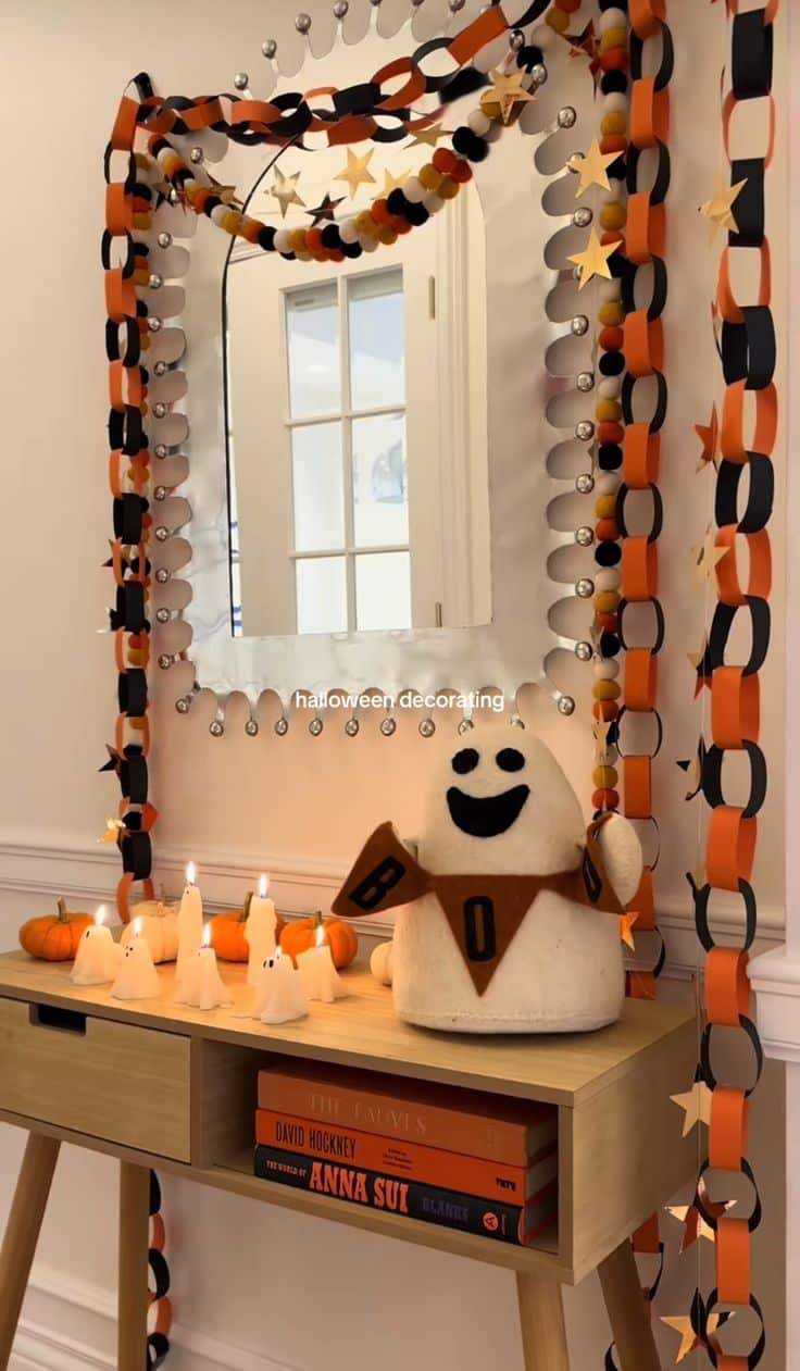 Orange, black and cream paper chain garland looped around an entryway mirror