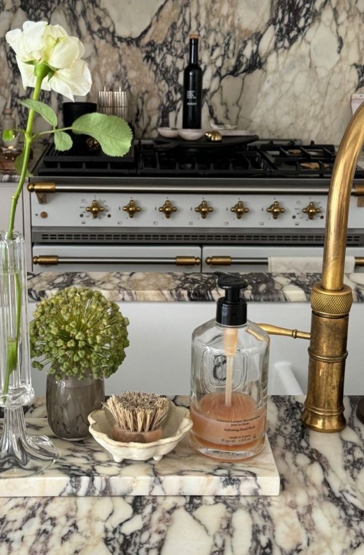 Marble slab styled with a glass hand wash bottle, a scalloped dish with a brush and slim bud vases