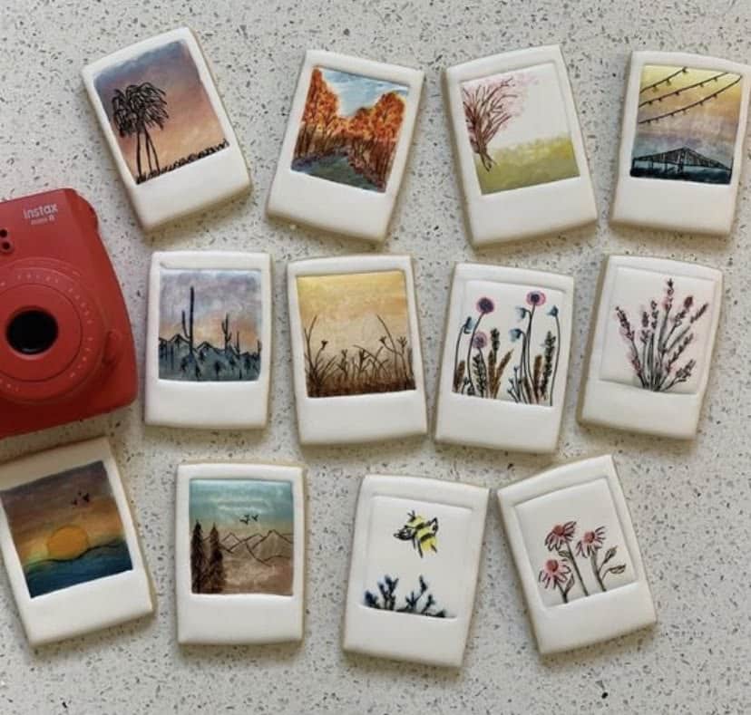 Clay polaroid magnets with hand-painted landscape scenes beside a red instax camera