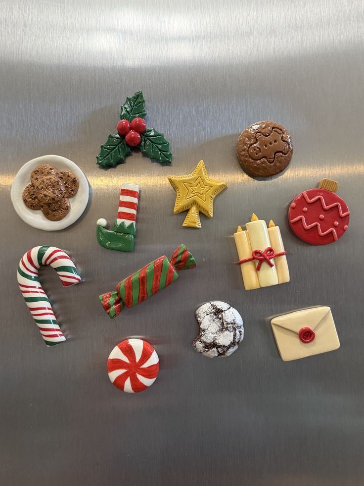Christmas clay magnets including a candy cane, holly, baubles, gingerbread and cookies on a stainless steel fridge