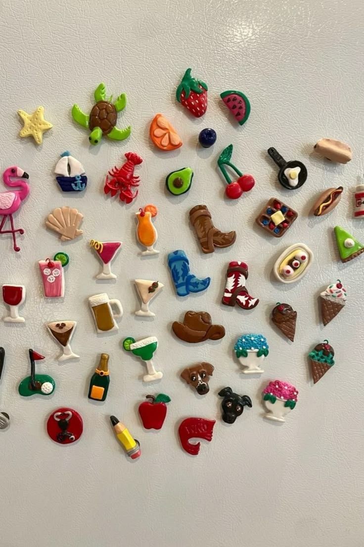 A large collection of tiny colourful novelty clay magnets including a flamingo, lobster, cocktails and ice cream cones
