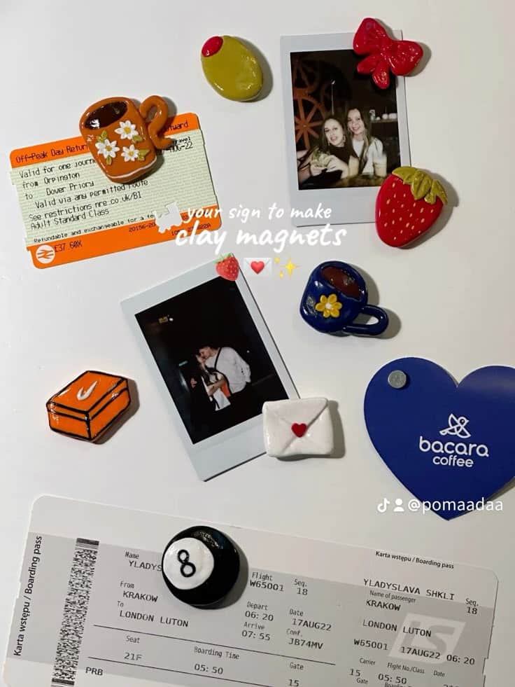 Clay keepsake magnets holding polaroid photos and travel tickets on a fridge, including a mug, strawberry and heart envelope