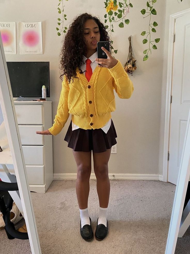 Person in a cropped yellow cardigan, white shirt with a red tie and dark pleated skirt, dressed as SpongeBob SquarePants.