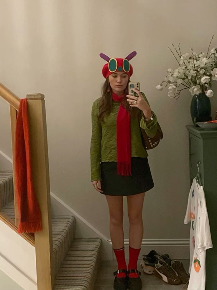 Person in a green top and red beret styled as the Very Hungry Caterpillar, with antennae and a red scarf.