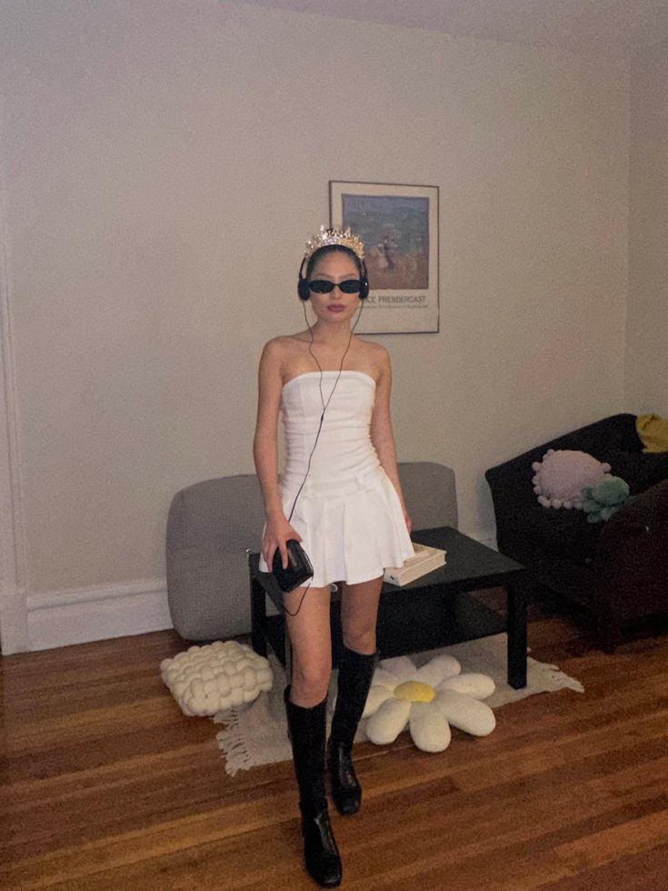 Person in a white pleated mini dress with knee boots, a tiara and dark sunglasses, dressed as Princess Mia from The Princess Diaries.