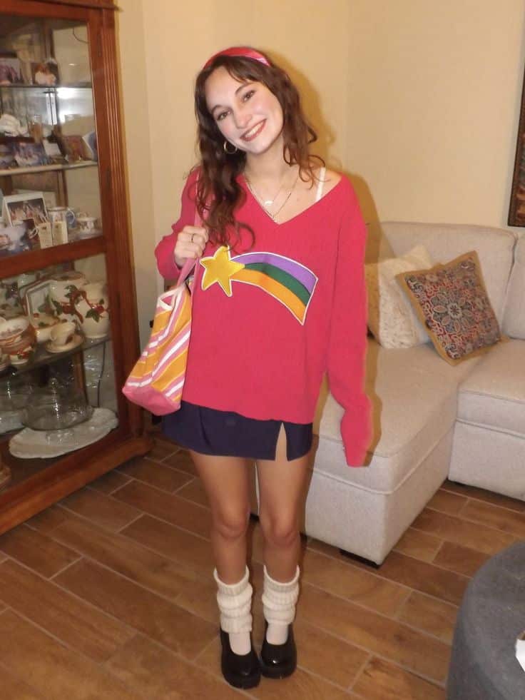 Person in a red shooting-star jumper, navy mini skirt and headband, dressed as Mabel Pines from Gravity Falls.