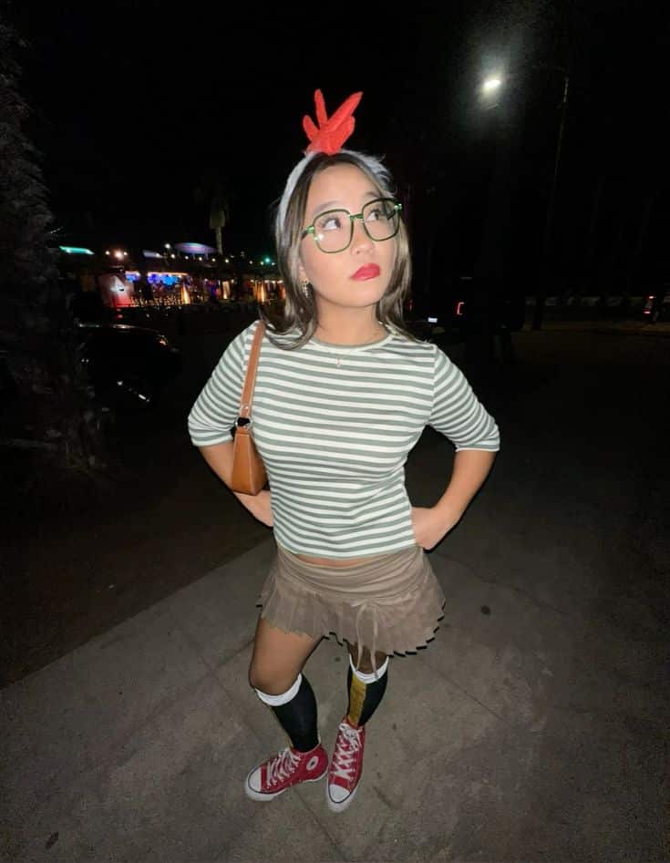 Person in a green-and-white striped top with round glasses and a red comb headband, dressed as Chicken Little.