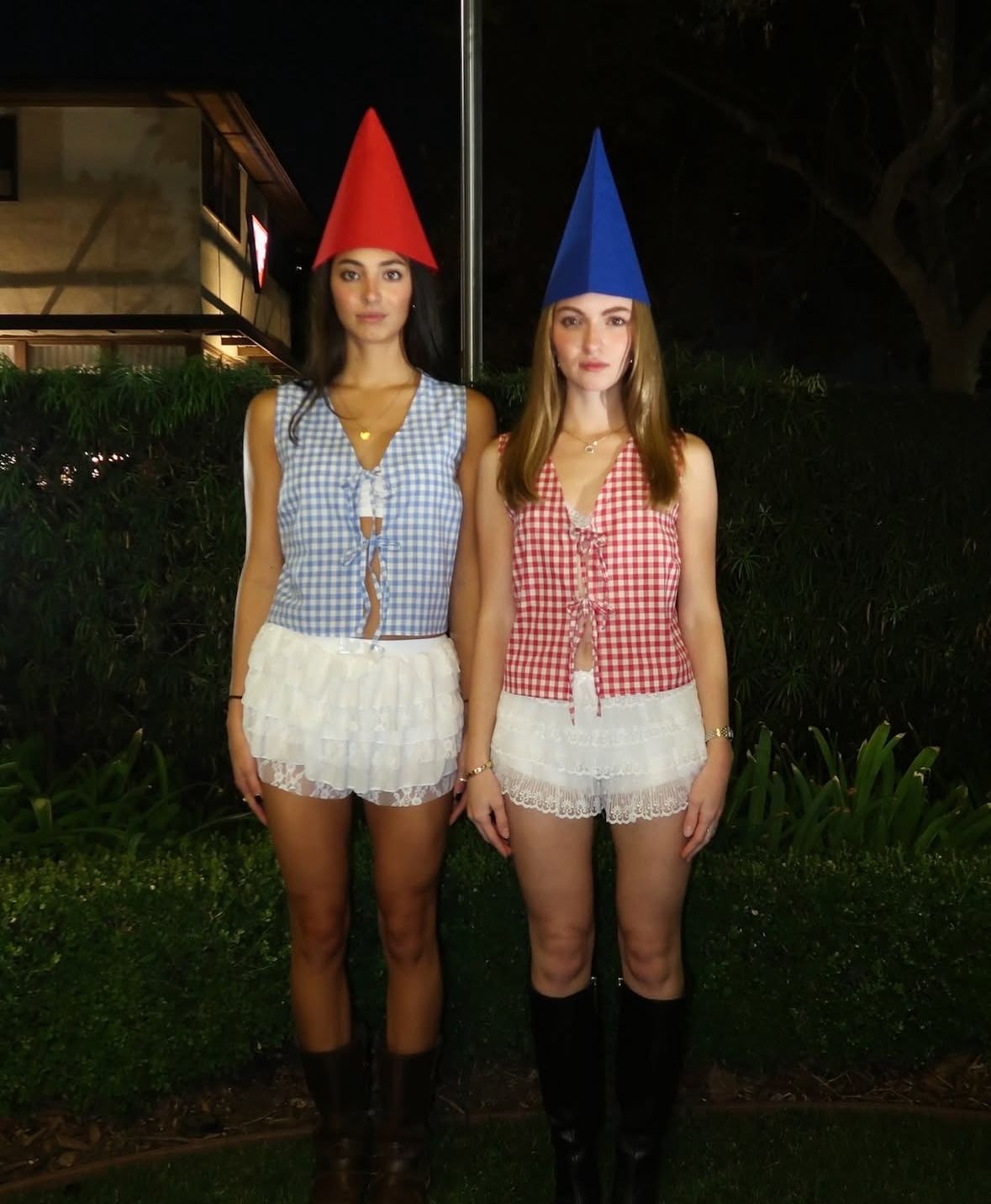 Two people in red and blue pointed gnome hats with gingham tops and white ruffled bottoms