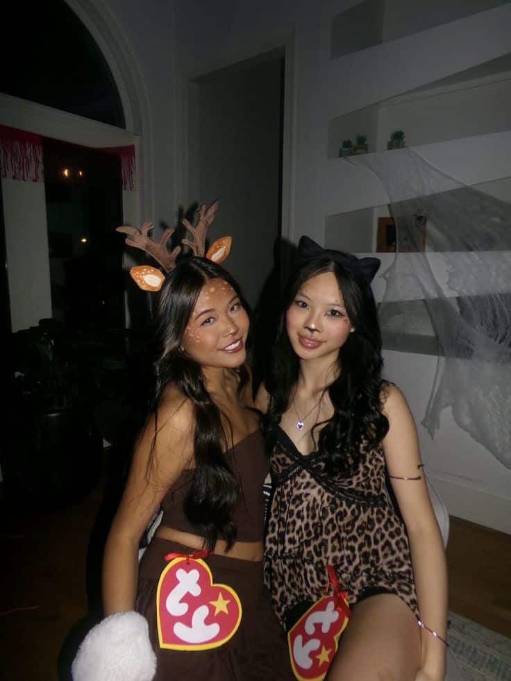 Two friends dressed as Beanie Babies, a deer and a cat, wearing large red Ty heart tags