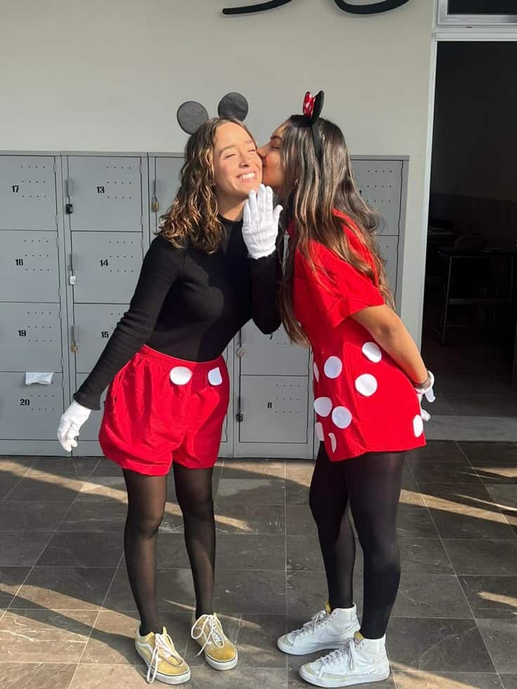 Two friends as Mickey and Minnie Mouse in red and black with mouse ears and white gloves