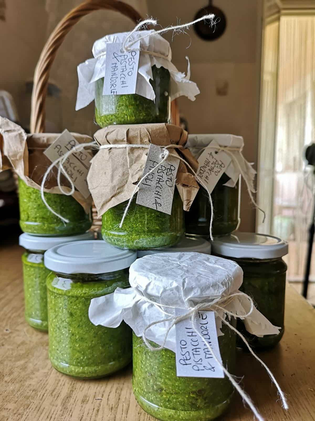 Jars of bright green pistachio pesto with paper covers, twine and handwritten tags