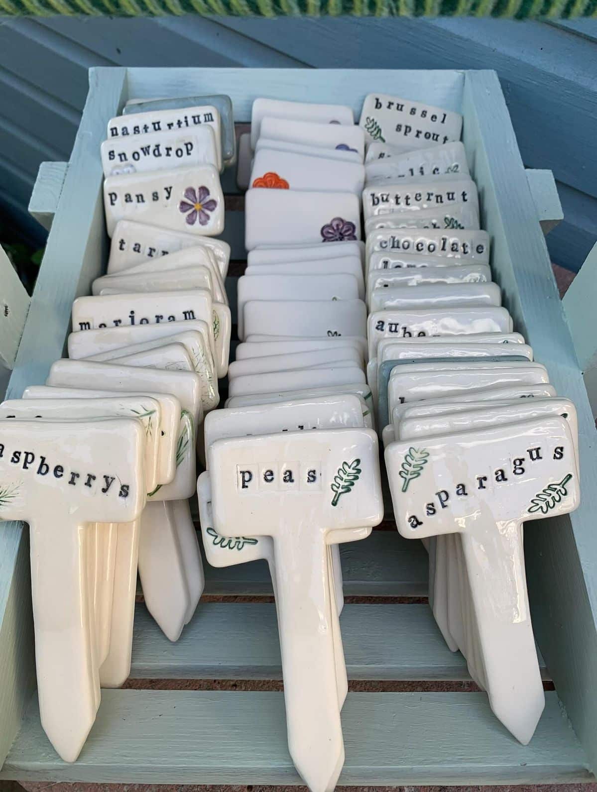 Tray of white ceramic plant markers stamped with herb, vegetable and flower names